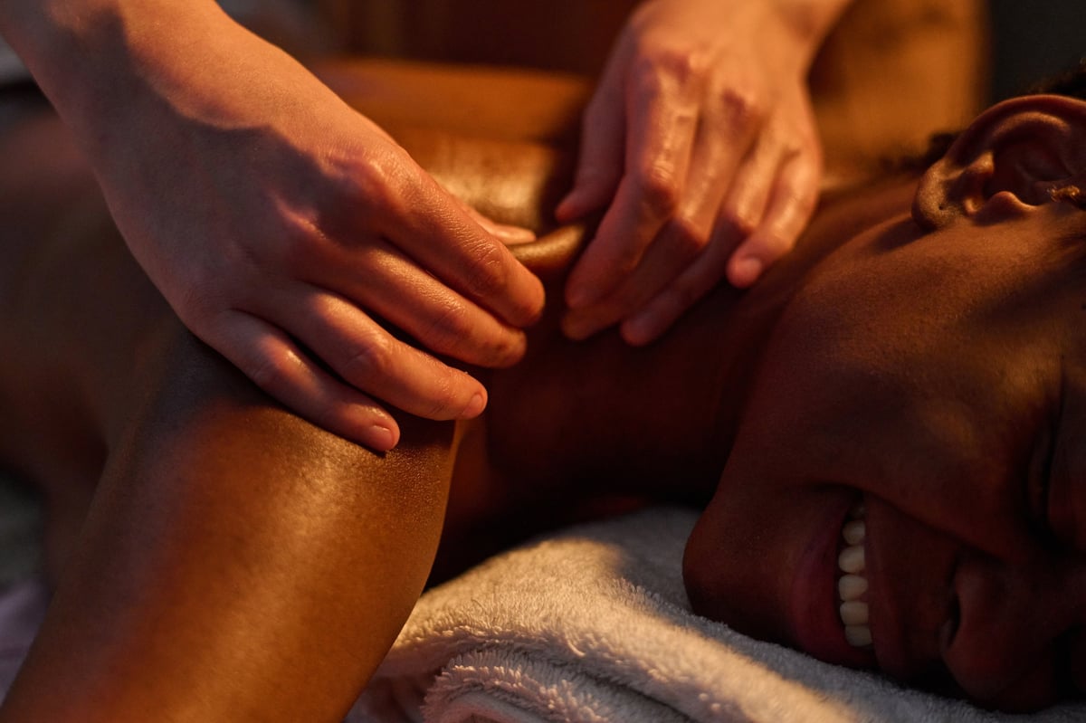 Masseuse using petrissage technique to massage deep shoulder muscles